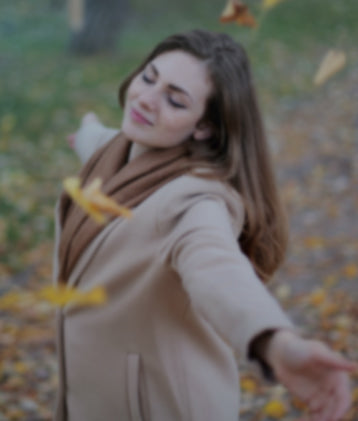 Woman playfully tossing leaves, representing relaxation from CBD and THC products.
